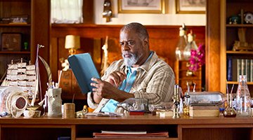 Man sitting in his office reading off of his ipad