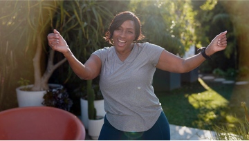 Woman in gray shirt dancing with her arms up.